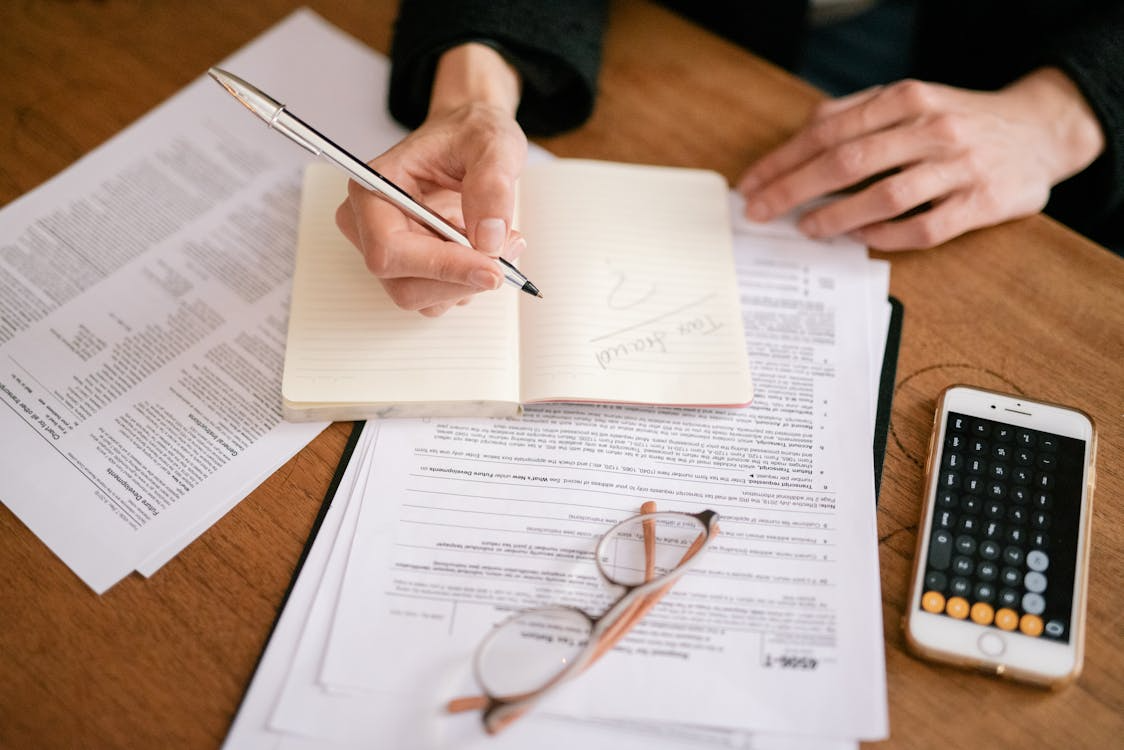 Finance professional reviewing invoices, tax documents, and calculations at a desk while identifying discrepancies tied to a potential sales tax refund.