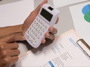 Finance professional manually reviewing an invoice and calculator, illustrating inefficient accounts payable workflows and slow invoice processing.
